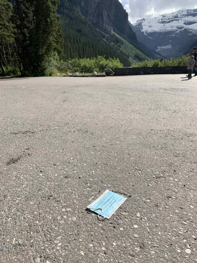 A single-use mask on the ground with mountains in the background