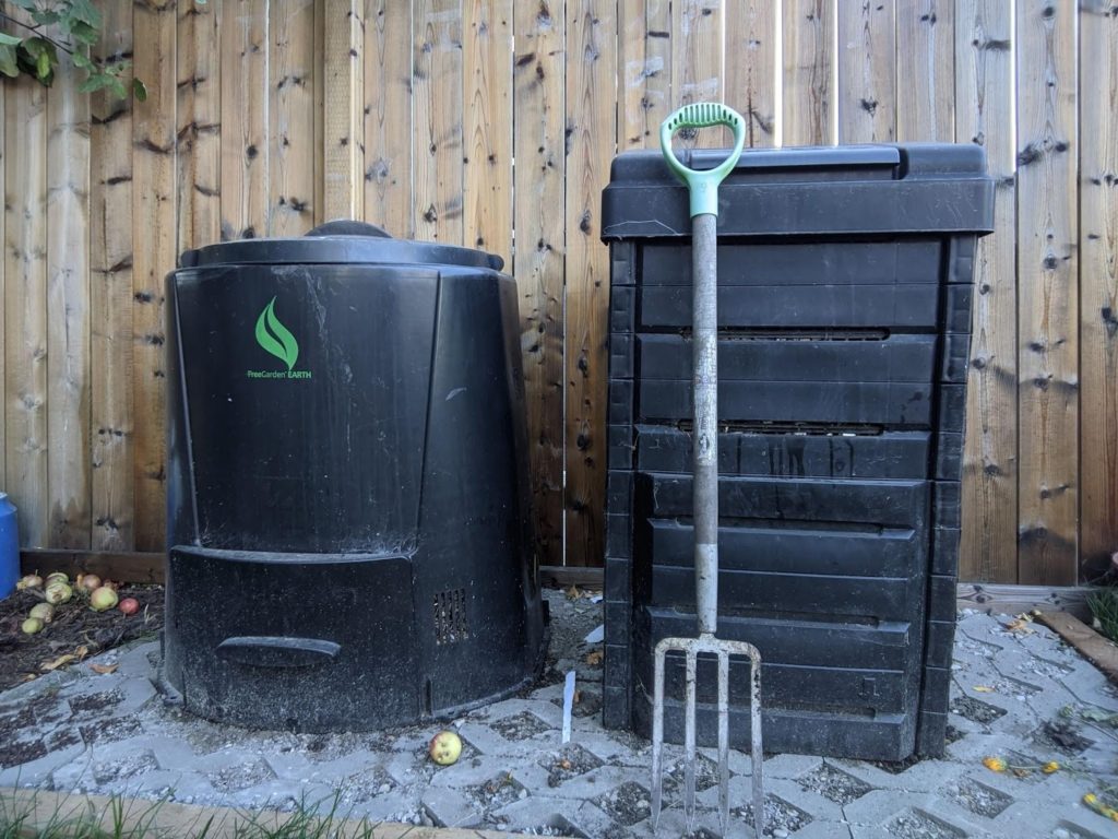 The equipment needed for backyard compost -- large plastic bins and a pitchfork.