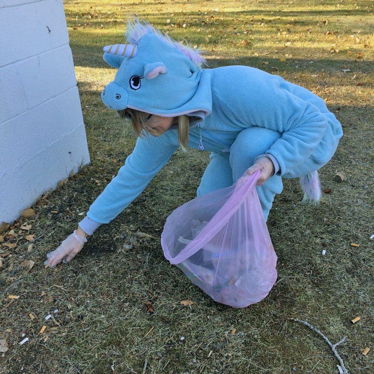 A woman in a unicorn costume picking up litter.